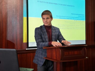 Євген Жураковський презентує дослідження на конференції в ІФННЮІ, виступ біля кафедри з гербом університету.